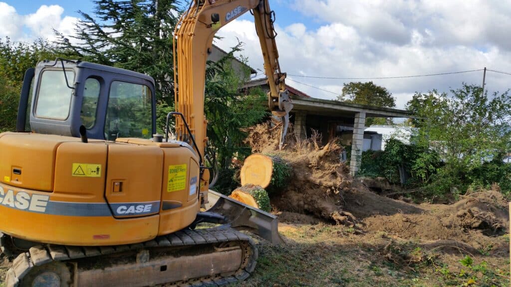Pelle CASE de l'Entreprise Bonnet Pierre déracinant une souche d'arbre sur un chantier de terrassement paysager.